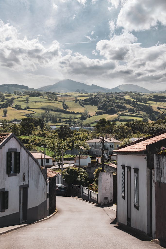 Picturesque view of Capelas village street with mountainous backdrop in the Azores, Portugal.