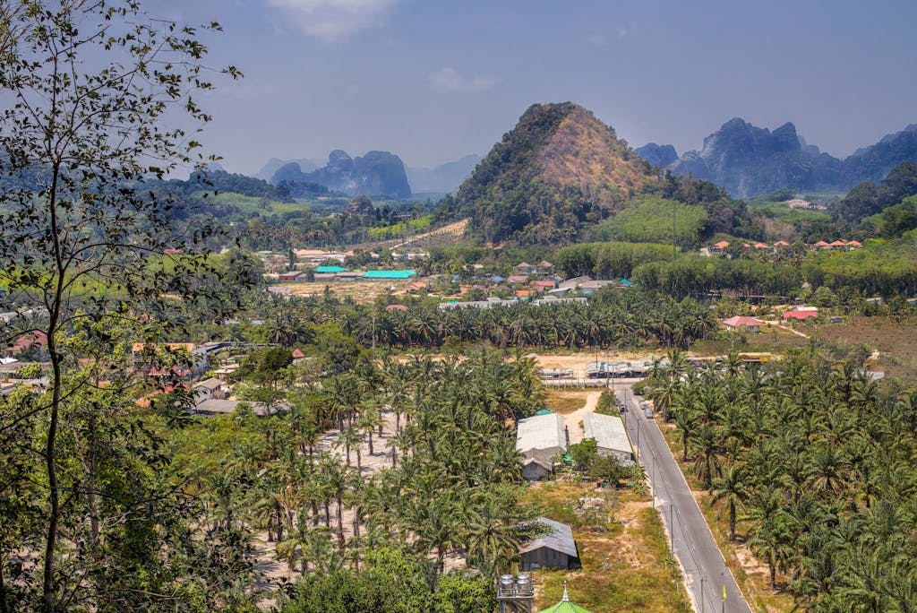 Scenic aerial view of Ao Nang, Thailand, featuring mountains, palm groves, and rural areas.