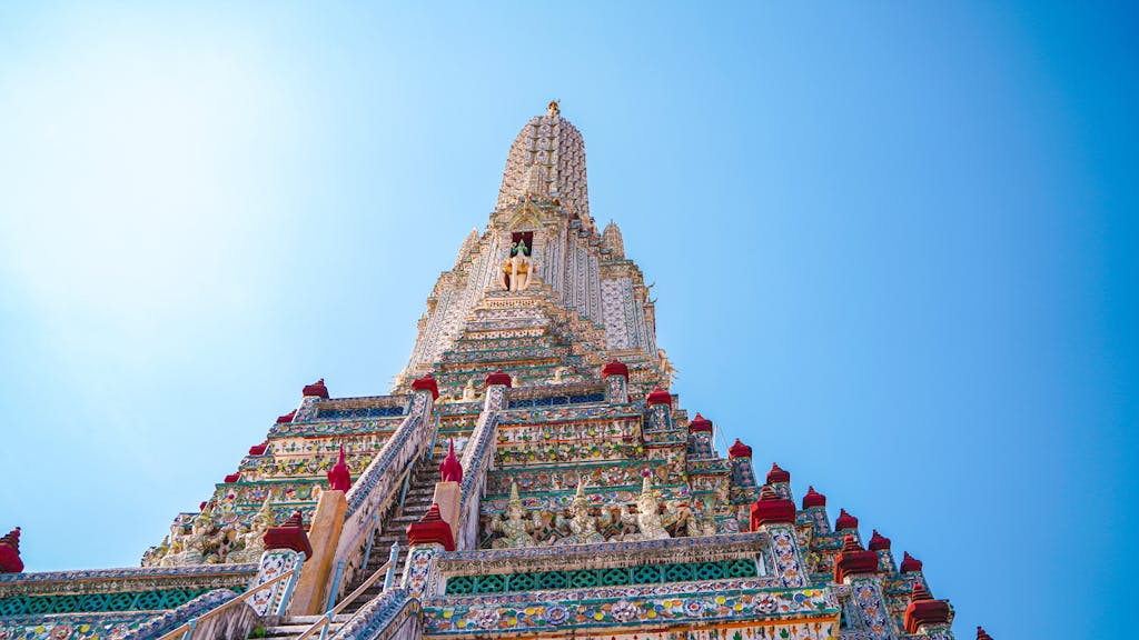 Stunning view of Wat Arun's intricate central tower in Bangkok under a clear blue sky.