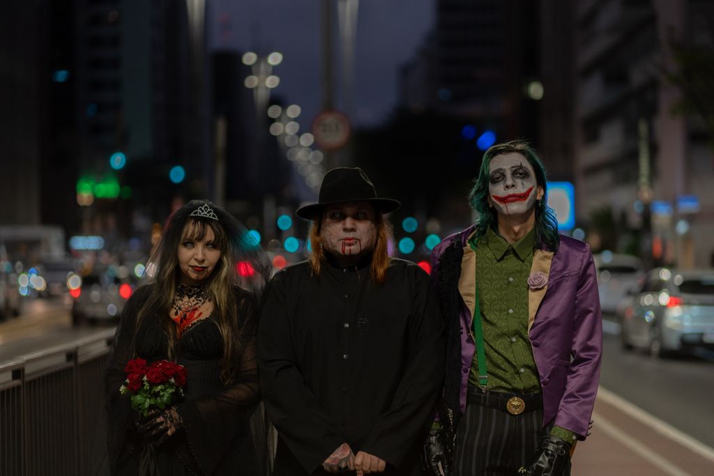 A trio in Halloween-themed cosplay walking through a bustling city street at night.