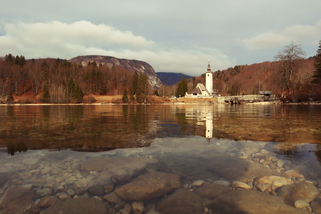 Beautiful autumn landscape of Lake Bohinj with church reflection in Slovenia's mountains.