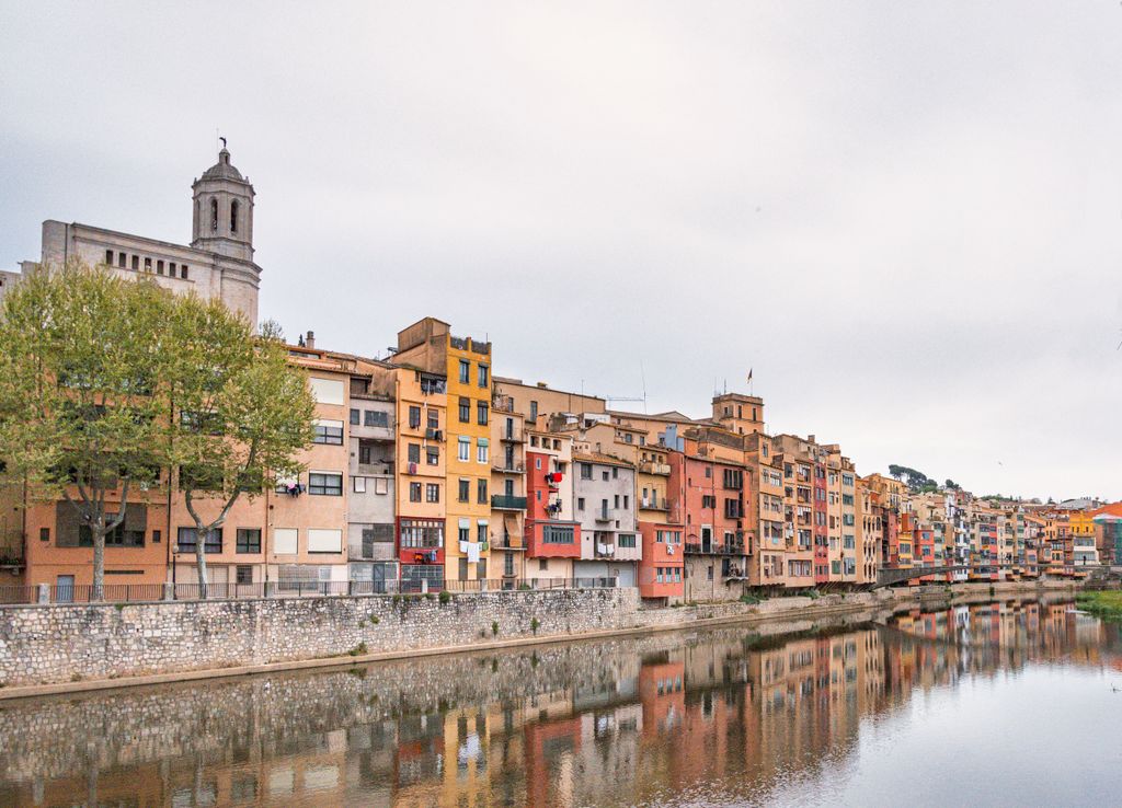 Colorful buildings along Onyar river in Girona, Spain, reflecting vibrant heritage.